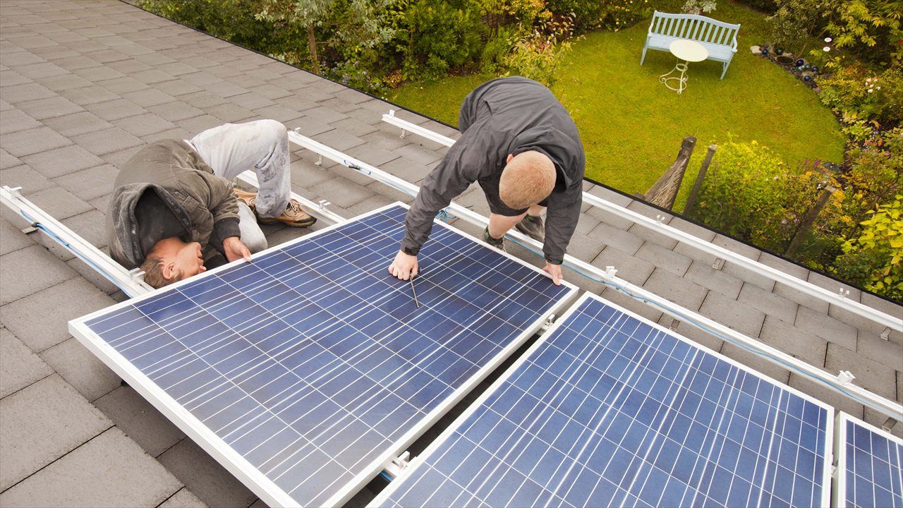 Twee installateurs leggen zonnepanelen op een schuin dak.